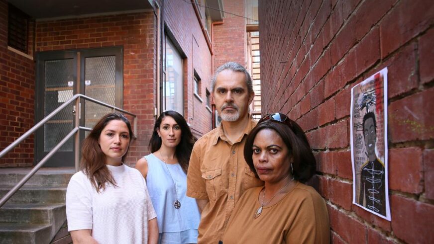 3 women and a man standing by a brick wall.